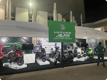 A Luyuan ALFA electric bikes exhibition stand lit up at an evening event