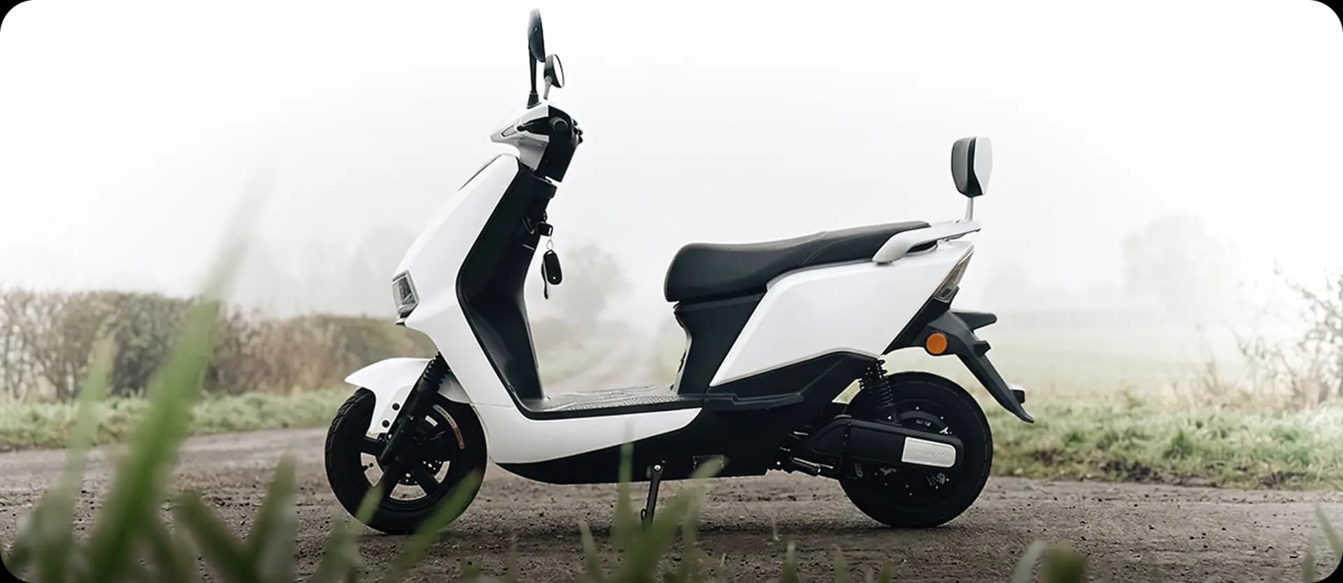 White electric scooter on a country road on a misty morning